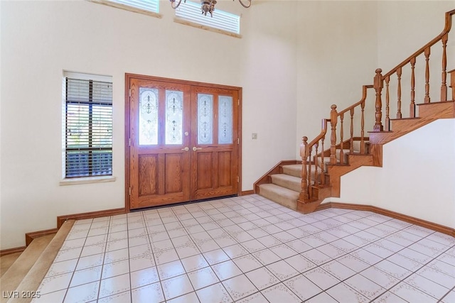 foyer with light tile patterned floors, a high ceiling, stairway, and baseboards