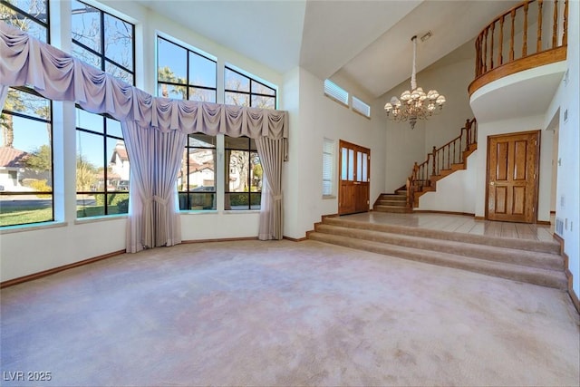 unfurnished living room with light carpet, a towering ceiling, and an inviting chandelier