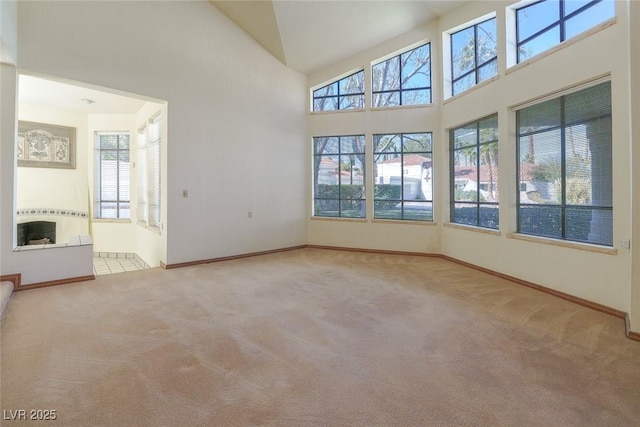 unfurnished room featuring a healthy amount of sunlight, a towering ceiling, and carpet flooring