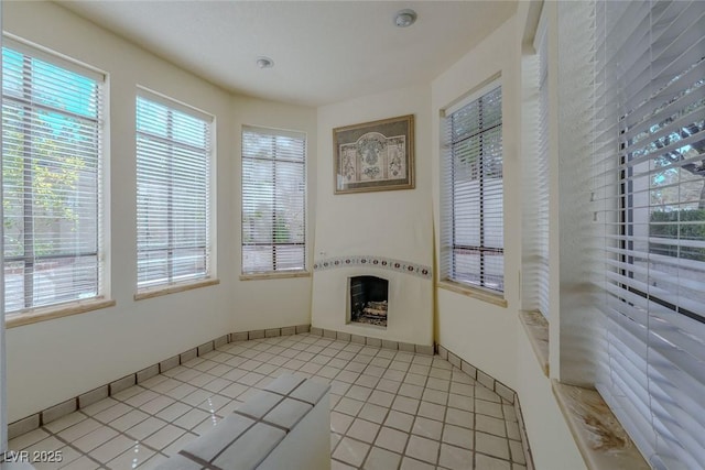 interior space with light tile patterned floors, a fireplace, and baseboards