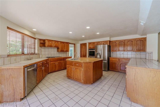 kitchen with a wealth of natural light, appliances with stainless steel finishes, a sink, and a kitchen island with sink