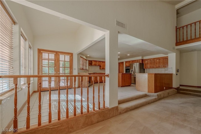 interior space featuring a towering ceiling, plenty of natural light, and visible vents