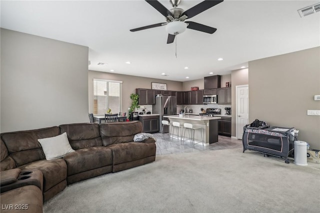 carpeted living room featuring ceiling fan and sink