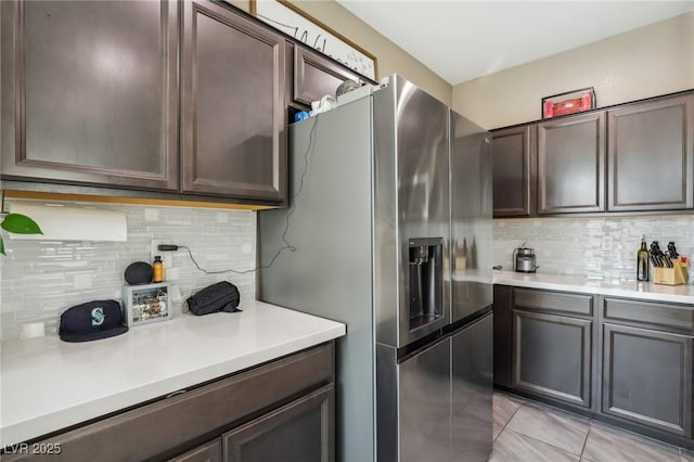 kitchen featuring dark brown cabinets, stainless steel fridge with ice dispenser, light tile patterned floors, and tasteful backsplash