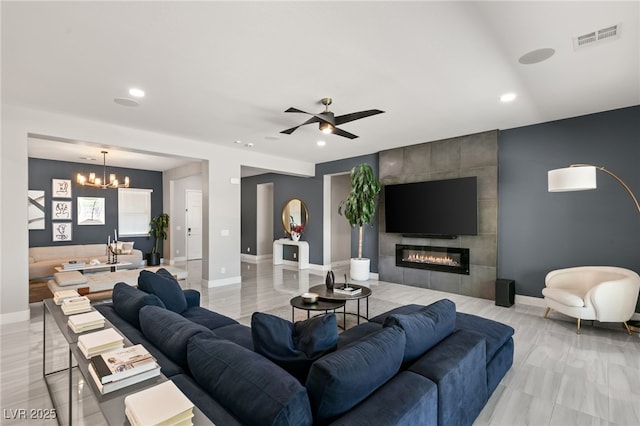 living room with a fireplace and ceiling fan with notable chandelier