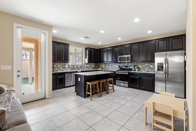 kitchen featuring a breakfast bar, a center island, sink, light tile patterned floors, and stainless steel appliances