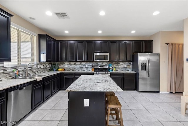 kitchen featuring a center island, stainless steel appliances, light stone counters, and sink