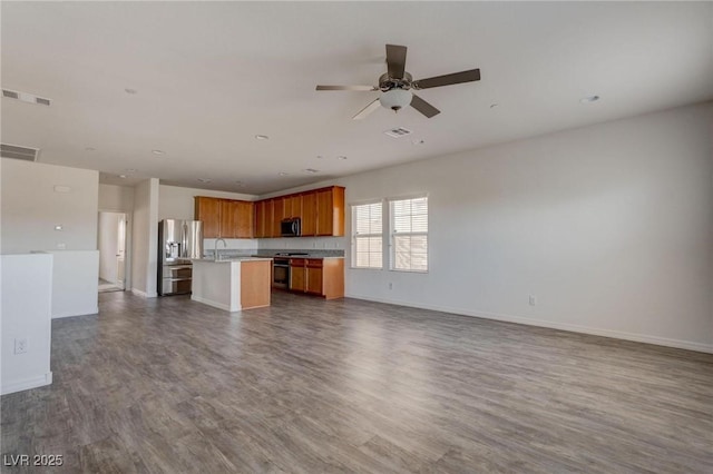 unfurnished living room with ceiling fan, sink, and hardwood / wood-style flooring