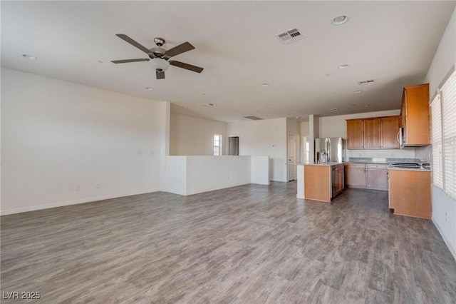 kitchen with ceiling fan, a kitchen island, stainless steel refrigerator with ice dispenser, and hardwood / wood-style flooring