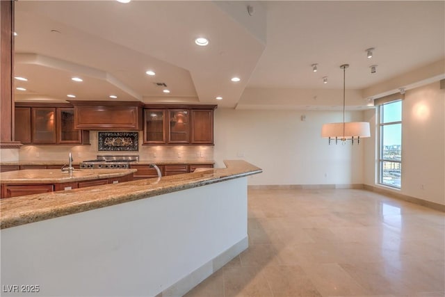 kitchen with decorative backsplash, light stone countertops, hanging light fixtures, and a notable chandelier