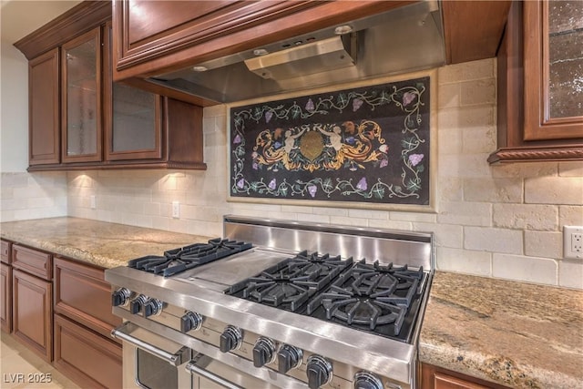 kitchen featuring custom exhaust hood, light stone countertops, high end stainless steel range, and tasteful backsplash