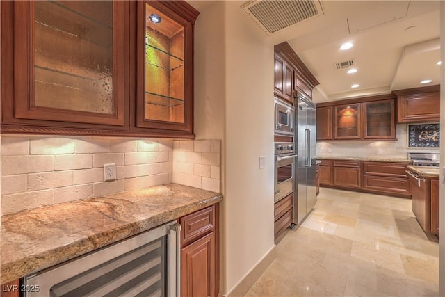 kitchen with decorative backsplash, built in appliances, light stone counters, and beverage cooler