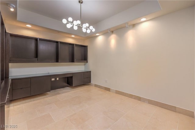 interior space with a tray ceiling, light tile patterned floors, and an inviting chandelier