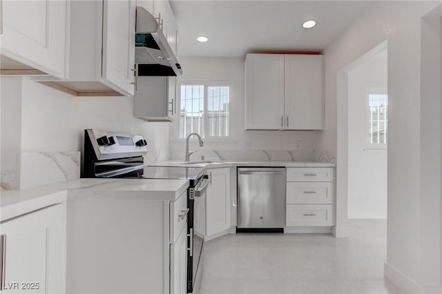 kitchen with appliances with stainless steel finishes, range hood, white cabinetry, sink, and light stone counters