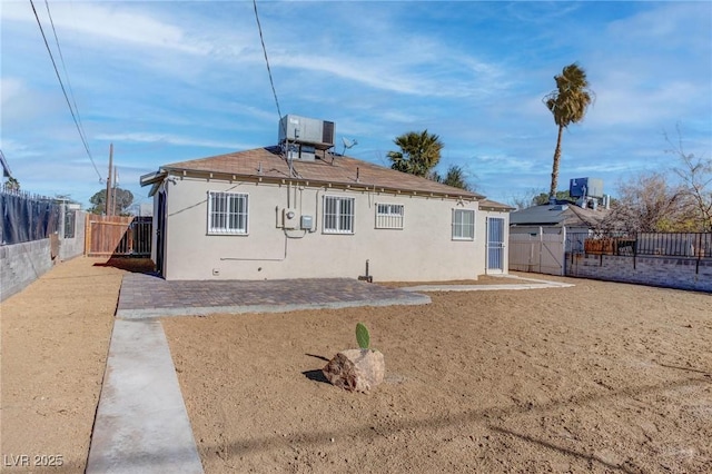 back of property with central AC unit and a patio