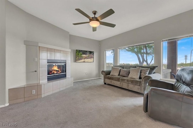 carpeted living room featuring ceiling fan and a tiled fireplace