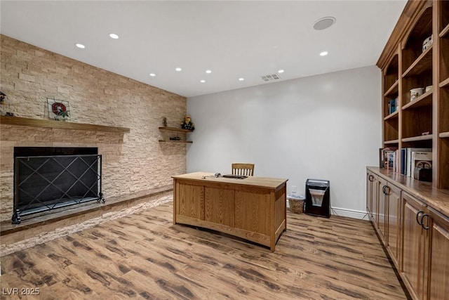 office area with hardwood / wood-style floors and a stone fireplace