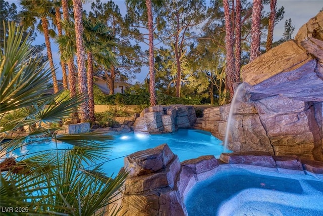 view of pool featuring pool water feature and a hot tub