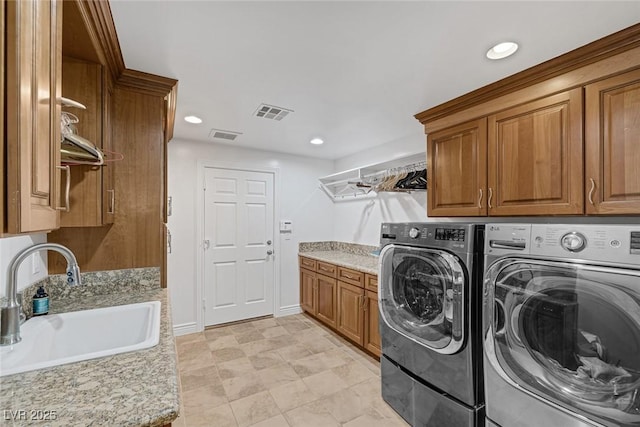 clothes washing area with cabinets, washer and clothes dryer, and sink