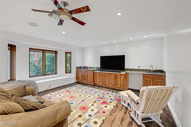 living room with light hardwood / wood-style floors, ceiling fan, and sink