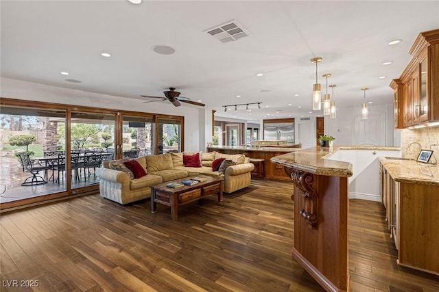 living room with dark hardwood / wood-style flooring, ceiling fan, and sink