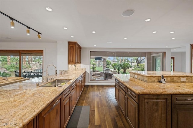 kitchen featuring backsplash, dark hardwood / wood-style flooring, light stone countertops, and sink