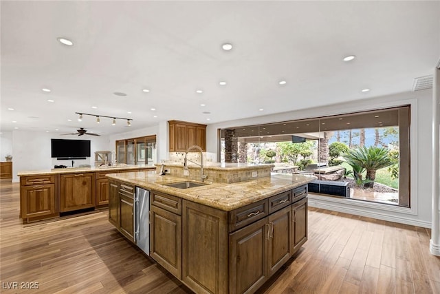 kitchen with a healthy amount of sunlight, a spacious island, light hardwood / wood-style floors, and sink