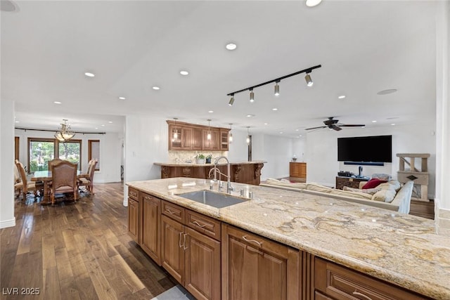 kitchen featuring ceiling fan, sink, tasteful backsplash, light stone counters, and dark hardwood / wood-style floors