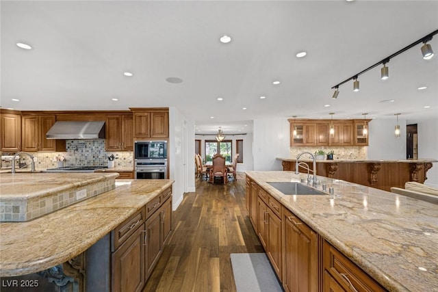 kitchen featuring appliances with stainless steel finishes, dark hardwood / wood-style flooring, wall chimney exhaust hood, sink, and hanging light fixtures