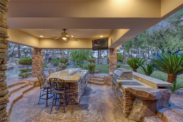 view of patio / terrace with exterior kitchen, area for grilling, a bar, and ceiling fan