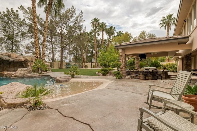 exterior space with ceiling fan, a patio area, and exterior bar