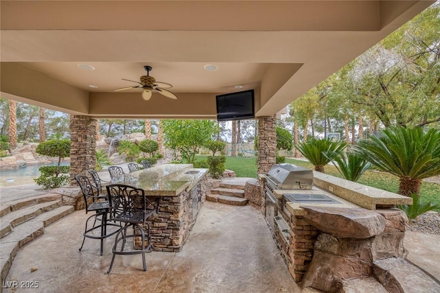 view of patio with area for grilling, grilling area, an outdoor bar, and ceiling fan