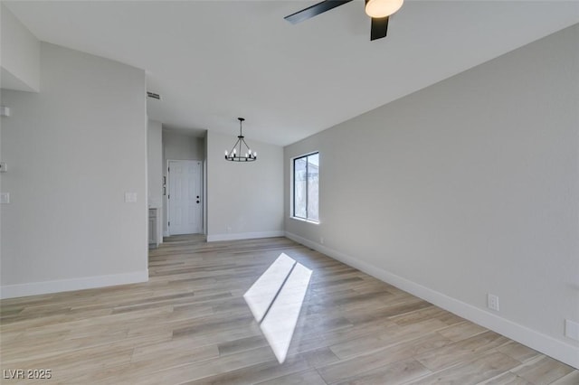 empty room with ceiling fan with notable chandelier, light wood-type flooring, and lofted ceiling