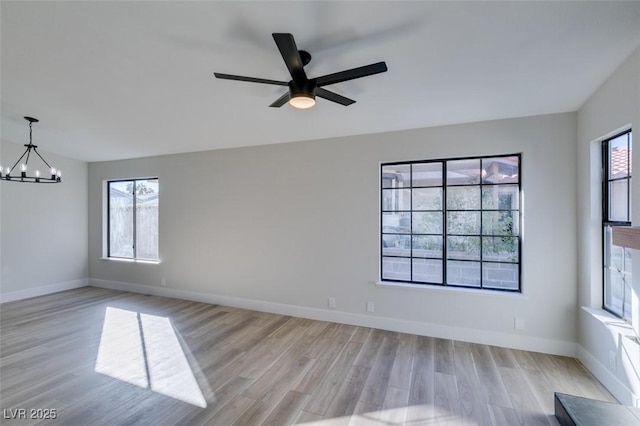 unfurnished room featuring ceiling fan with notable chandelier and light wood-type flooring