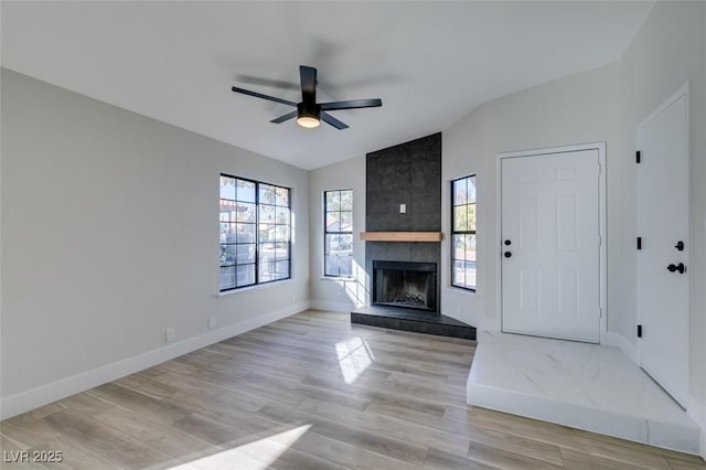 unfurnished living room with ceiling fan, a fireplace, lofted ceiling, and light hardwood / wood-style flooring