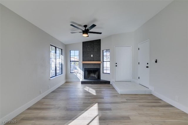 unfurnished living room with ceiling fan, light hardwood / wood-style flooring, a fireplace, and vaulted ceiling