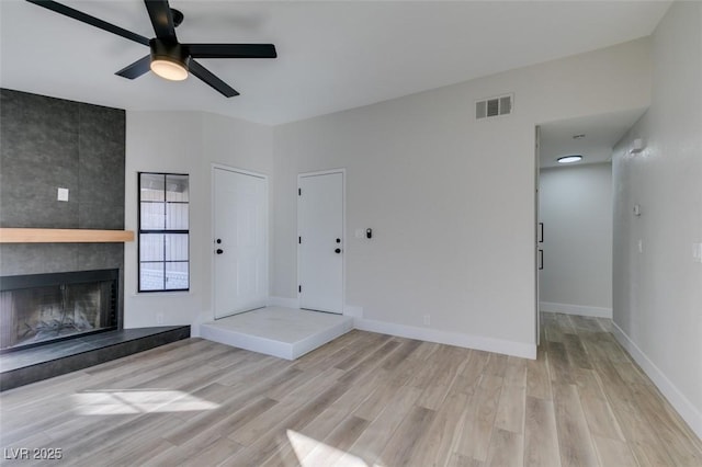 unfurnished living room with ceiling fan, light hardwood / wood-style floors, and a fireplace