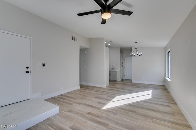 unfurnished living room featuring ceiling fan with notable chandelier, sink, and light hardwood / wood-style flooring