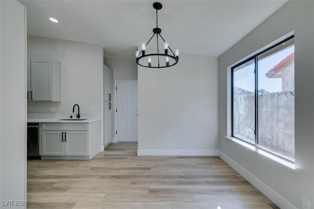 unfurnished dining area featuring sink, light wood-type flooring, and a notable chandelier