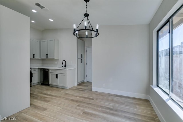 kitchen with light wood-type flooring, decorative light fixtures, a notable chandelier, dishwasher, and white cabinetry