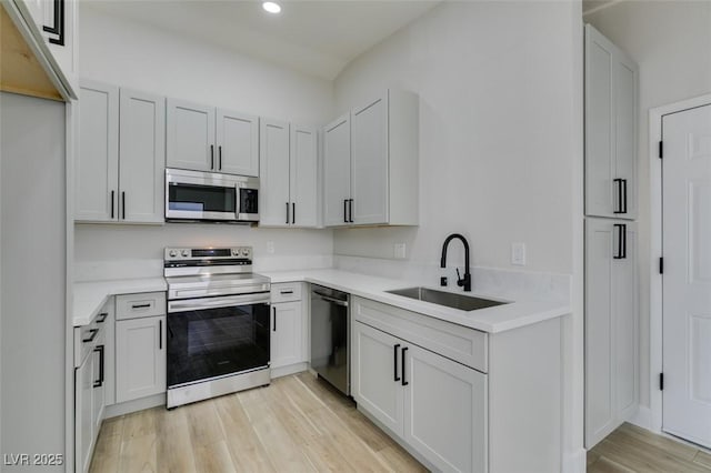 kitchen with light hardwood / wood-style floors, sink, white cabinetry, and stainless steel appliances