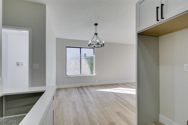 unfurnished dining area with sink, light hardwood / wood-style flooring, and a chandelier