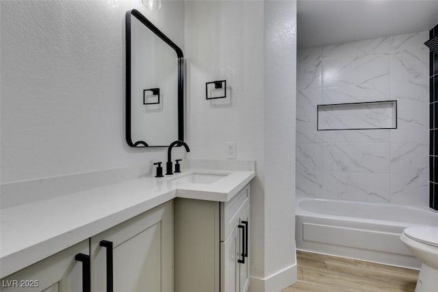 full bathroom with hardwood / wood-style flooring, vanity, toilet, and tiled shower / bath