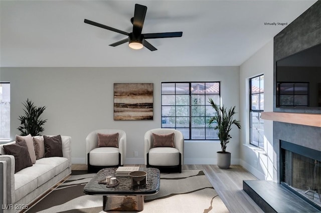 living room with ceiling fan, light hardwood / wood-style floors, and a fireplace