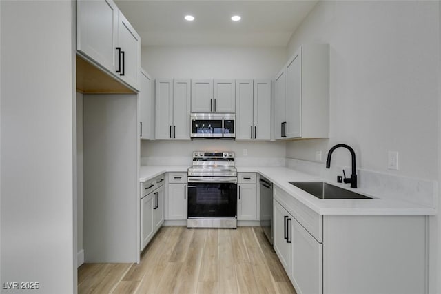 kitchen featuring white cabinets, light wood-type flooring, sink, and appliances with stainless steel finishes