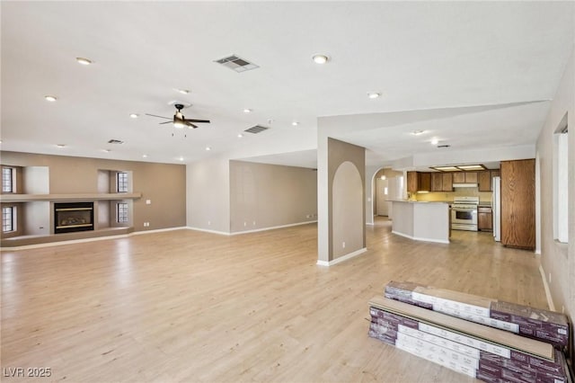 unfurnished living room featuring lofted ceiling, ceiling fan, and light wood-type flooring