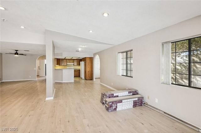 unfurnished living room with ceiling fan, light wood-type flooring, and vaulted ceiling