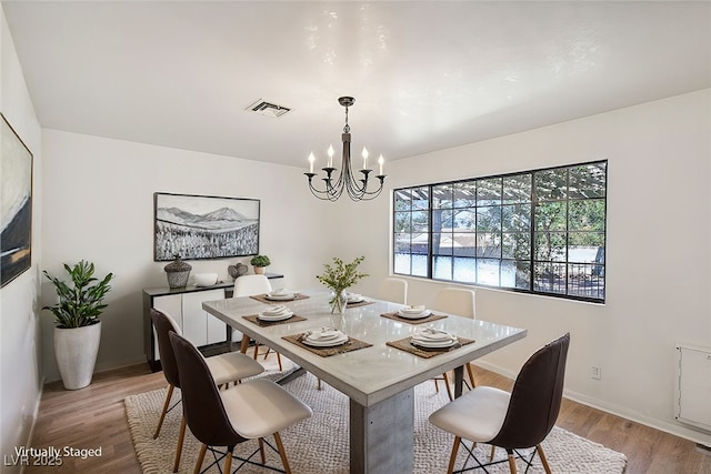 dining space with a notable chandelier and light hardwood / wood-style flooring