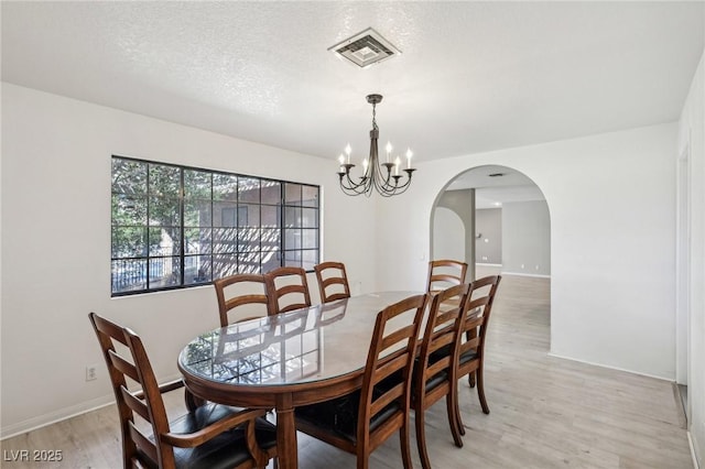 dining room featuring an inviting chandelier, a textured ceiling, and light hardwood / wood-style flooring