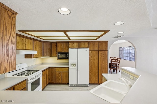 kitchen featuring white appliances, a textured ceiling, and sink